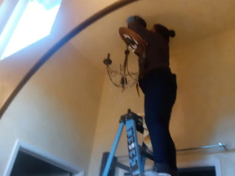 Electrician installing a chandelier in a Crowley residence